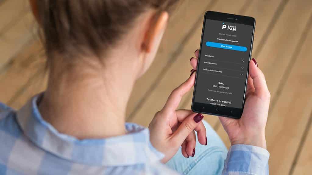 Imagem de uma pessoa segurando celular no app do Banco PAN