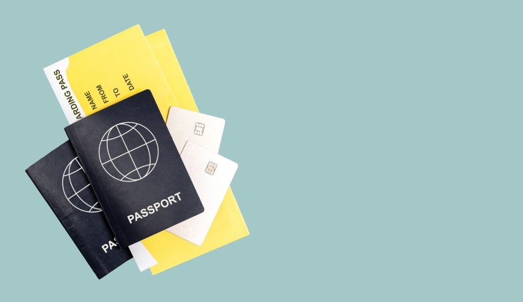 Two passports and credit cards next to yellow boarding passes on a pastel background, representing frequent flyer rewards and air miles accumulation.